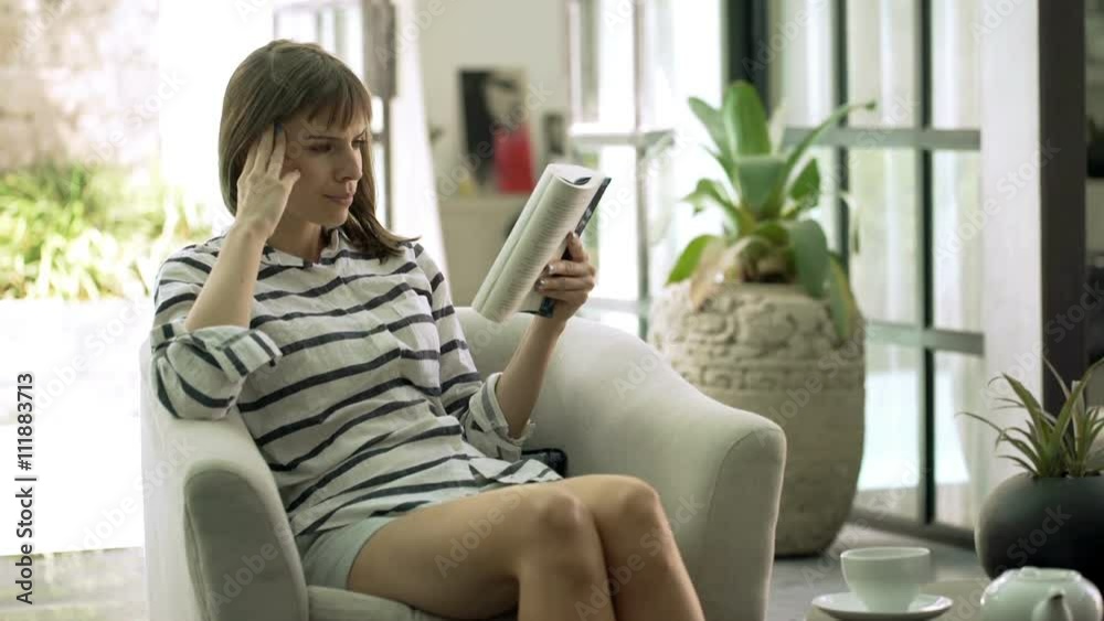 Young woman reading book while sitting on armchair at home
Young woman reading book while sitting on armchair at home