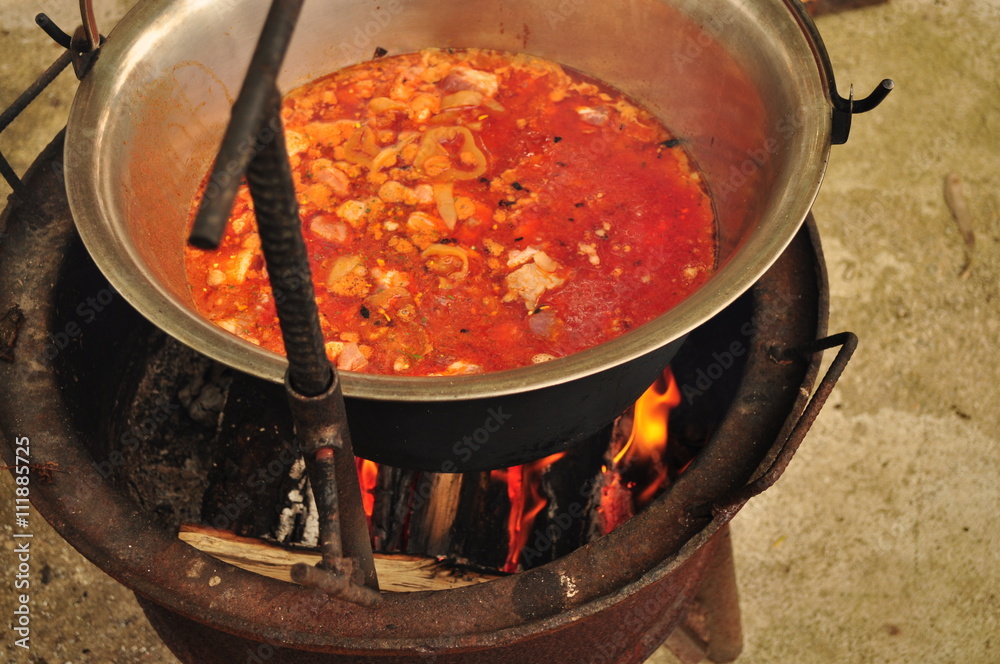 Traditional Goulash soup is boiling in the a cauldron Traditional Goulash soup is boiling in the a cauldron