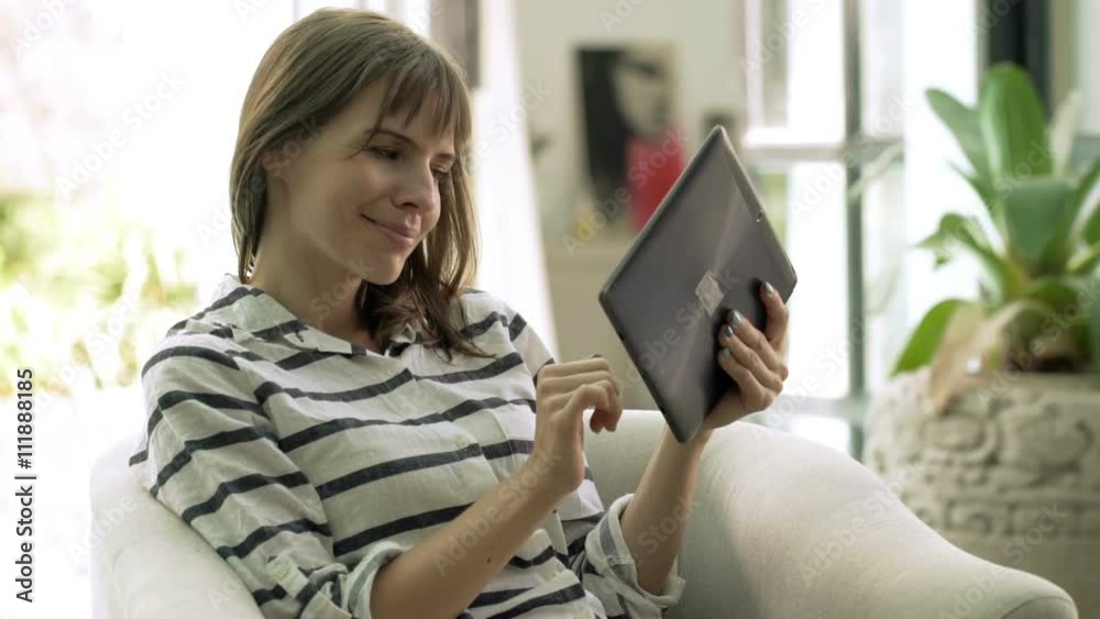 Young woman using tablet computer while sitting on armchair at home
Young woman using tablet computer while sitting on armchair at home