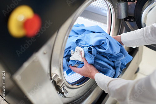 Hands to load the Laundry in the washing machine at the dry cleaners photo