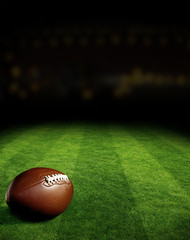American football on green field stadium at night