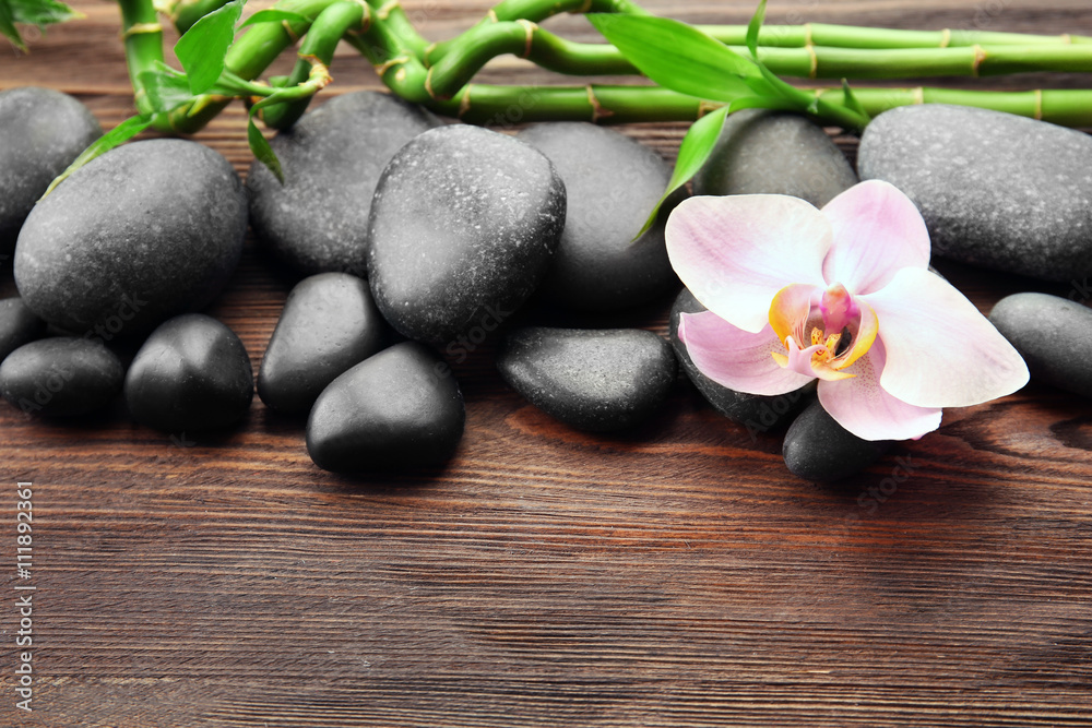 Spa stones and orchid flower on wooden background Spa stones and orchid flower on wooden background
