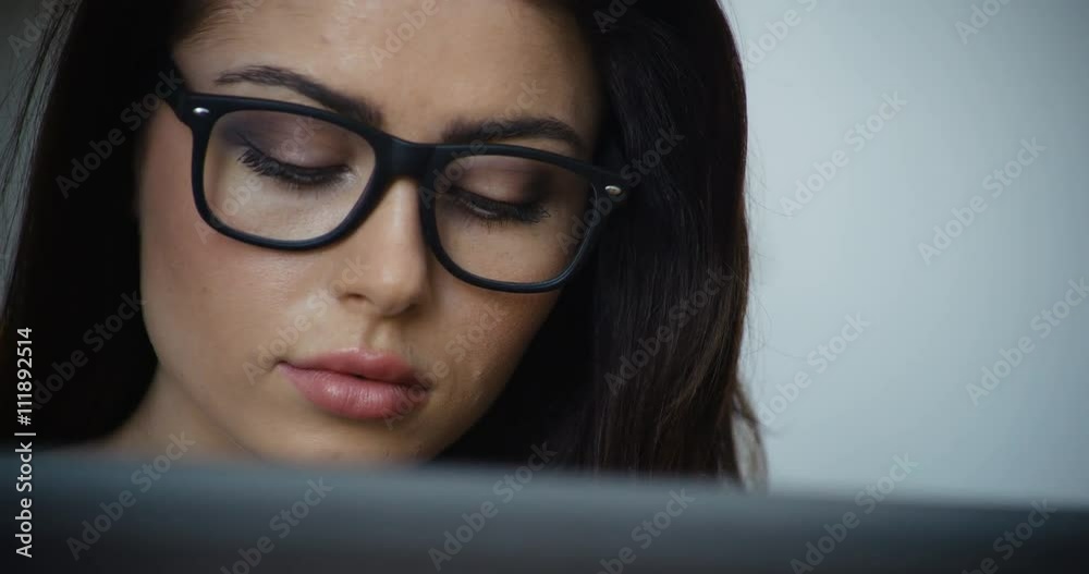 Beautiful brunette woman with brown hair and glasses using a laptop computer, close-up Beautiful brunette woman with brown hair and glasses using a laptop computer, close-up