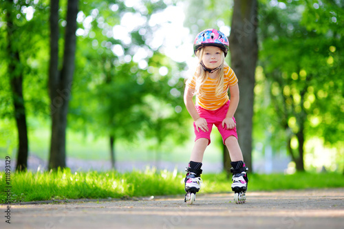 Pretty little girl learning to roller skate outdoors