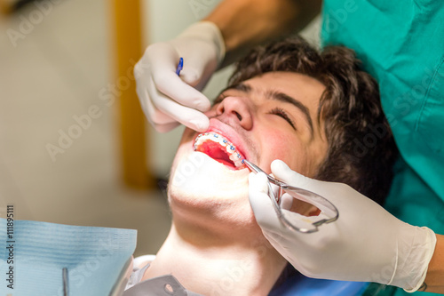 boy and orthodontist inserting blue ligatures photo