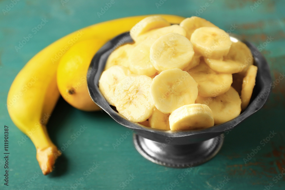 Banana slices in bowl on blue wooden background Banana slices in bowl on blue wooden background