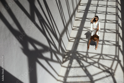 raven haired indian lady posing in geometrical shadows of metal stractures