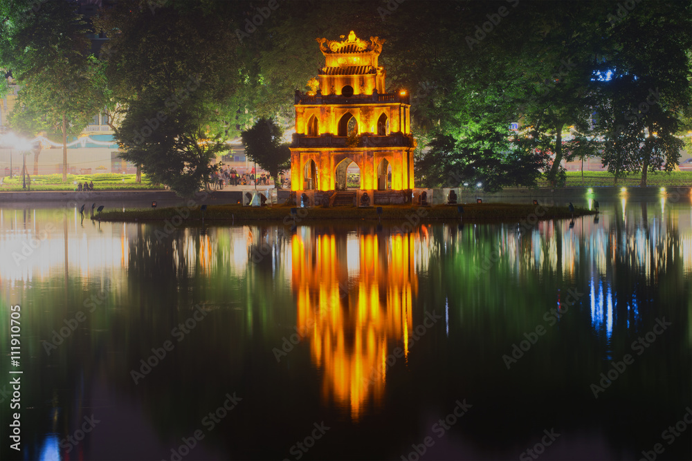 Fototapeta premium Ancient Temple of Turtles on the background of the waterfront Hoan Kiem lake in the night illumination. Hanoi, Vietnam