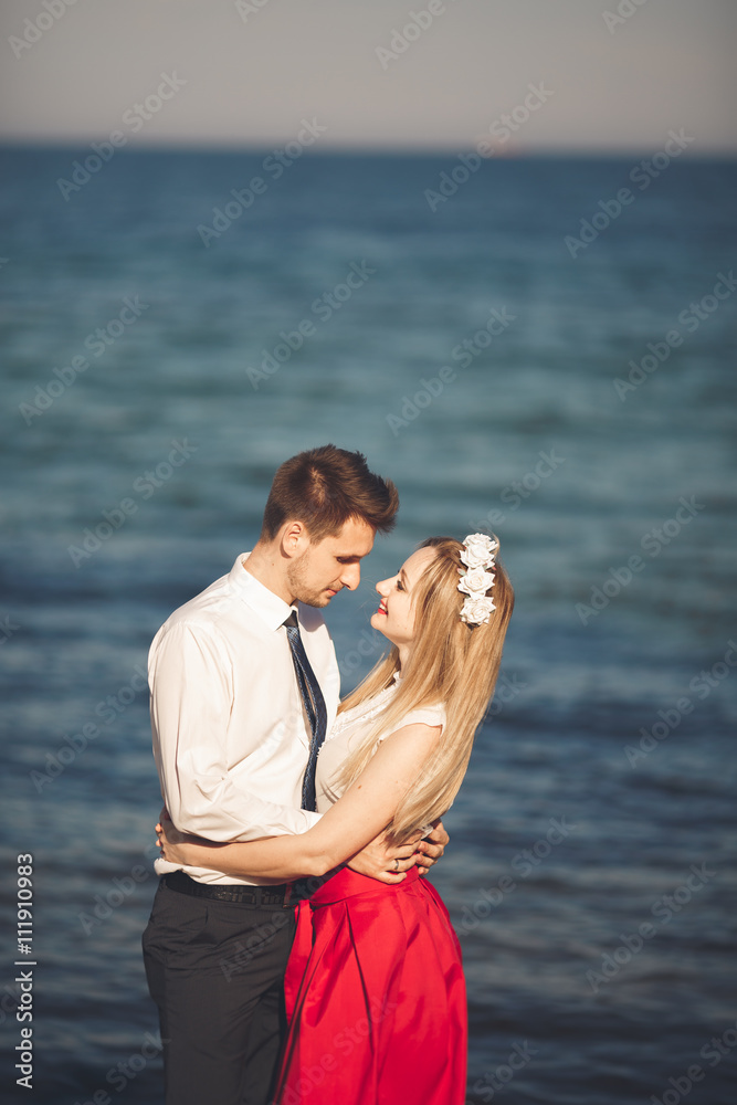 Young happy couple walking on beach smiling holding around each other. Love story