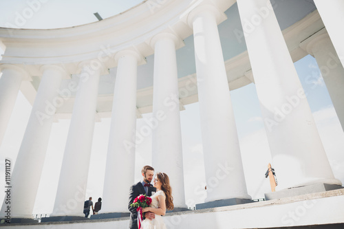 Beautiful couple, bride and groom posing near big white column