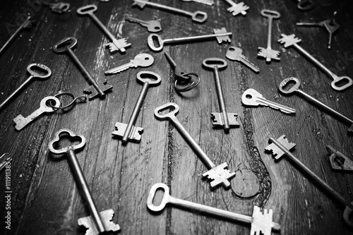 Some door keys on old wooden surface, safety, security concept background. Black and white photo