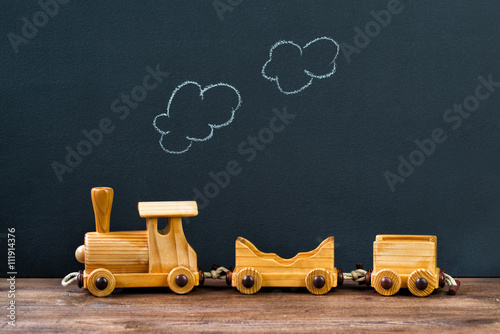 Old wooden toy train with steam on the chalkboard background