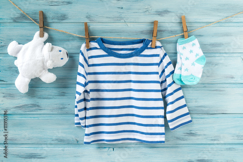 Baby boy striped shirt, socks with stars and white toy bear on a clothesline