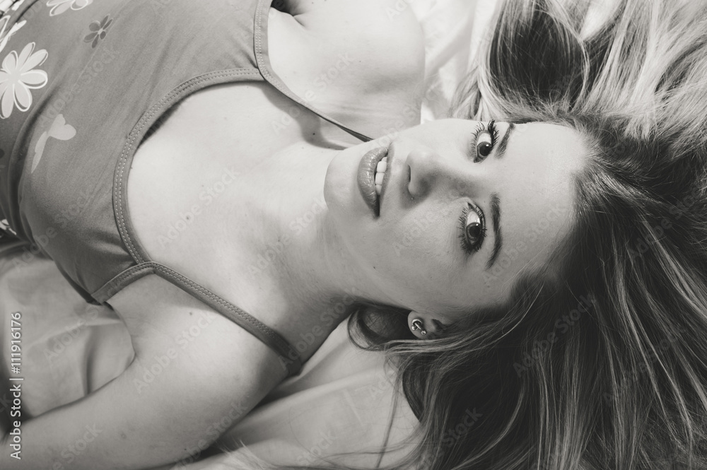Fototapeta premium Beautiful young adult attractive blonde woman in pajamas on bed