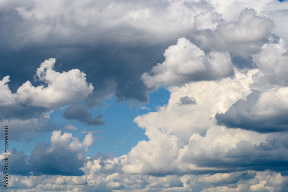 Fototapeta premium White Cumulus Clouds And Grey Storm Clouds Gathering On Blue Sky