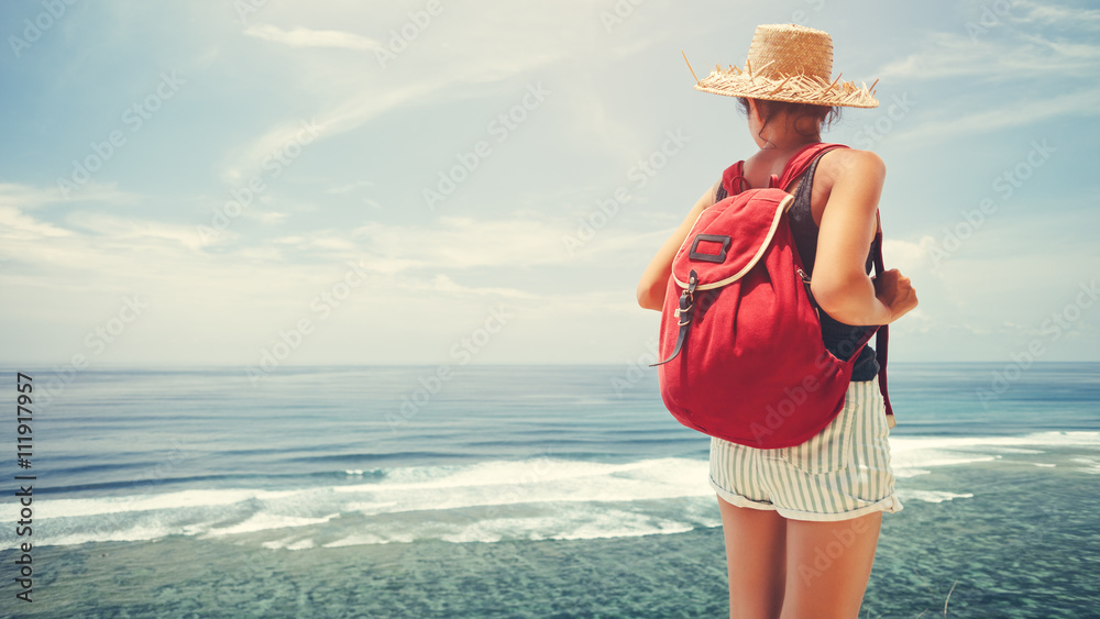 Young traveler with backpack looking at the ocean