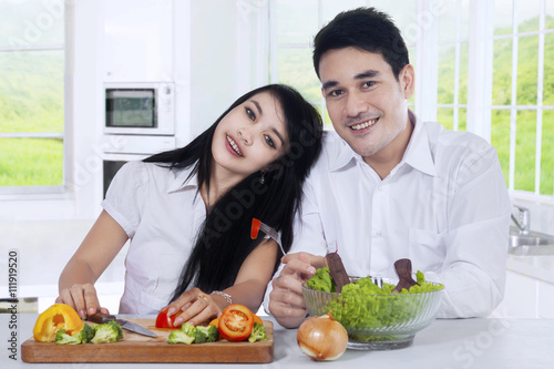 Happy couple with salad in the kitchen