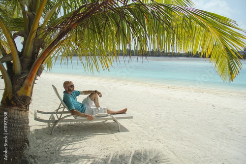  bald  man on a sun lounger under a palm tree in the Maldivian b © vrangel