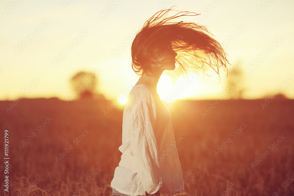 Obraz premium girl with long hair at sunset in the field