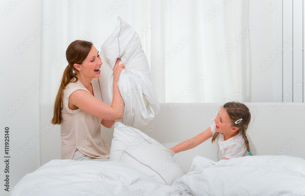 Mutter und Tochter bei Kissenschlacht auf dem Bett Mutter und Tochter bei Kissenschlacht auf dem Bett