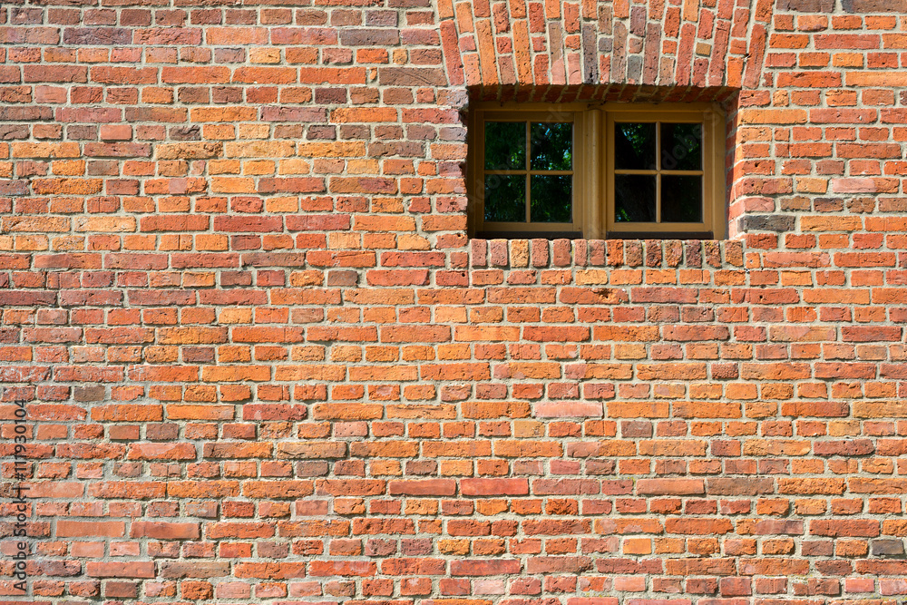 Small barred window in an old brick wall. The metal bars of the