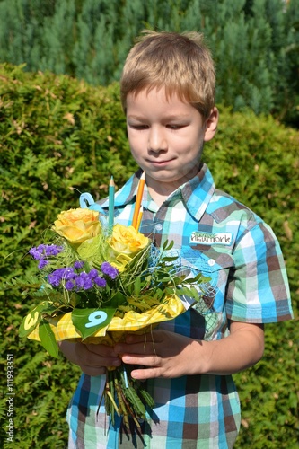 Junge betrachtet Blumenstrauß zum Schulanfang mit Stiften und Zahlen © alisseja