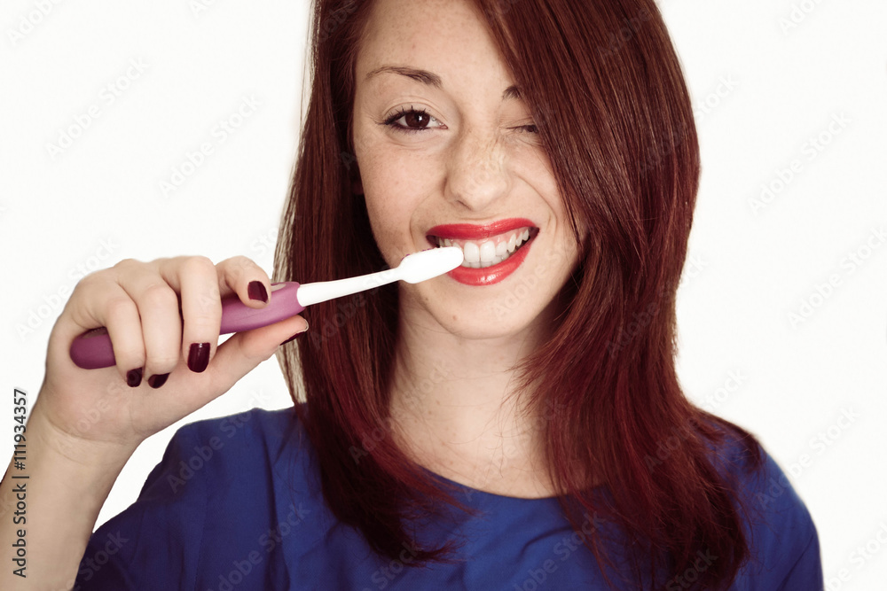 Portrait of a young and caucasian woman smiling with a toothbrush in her hand, isolated on white background- health, wellness and people concpet Portrait of a young and caucasian woman smiling with a toothbrush in her hand, isolated on white background- health, wellness and people concpet