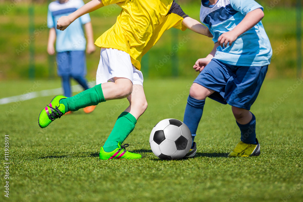 Training and football match between youth soccer teams. Boys kicking soccer football ball. Young soccer football players playing match at sports field Training and football match between youth soccer teams. Boys kicking soccer football ball. Young soccer football players playing match at sports field