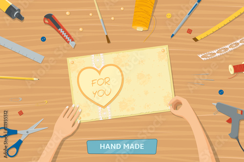 View from the top of table with instruments for hand made. Woman making gift card. Hands of woman. Tools for scrapbooking lying on a table.