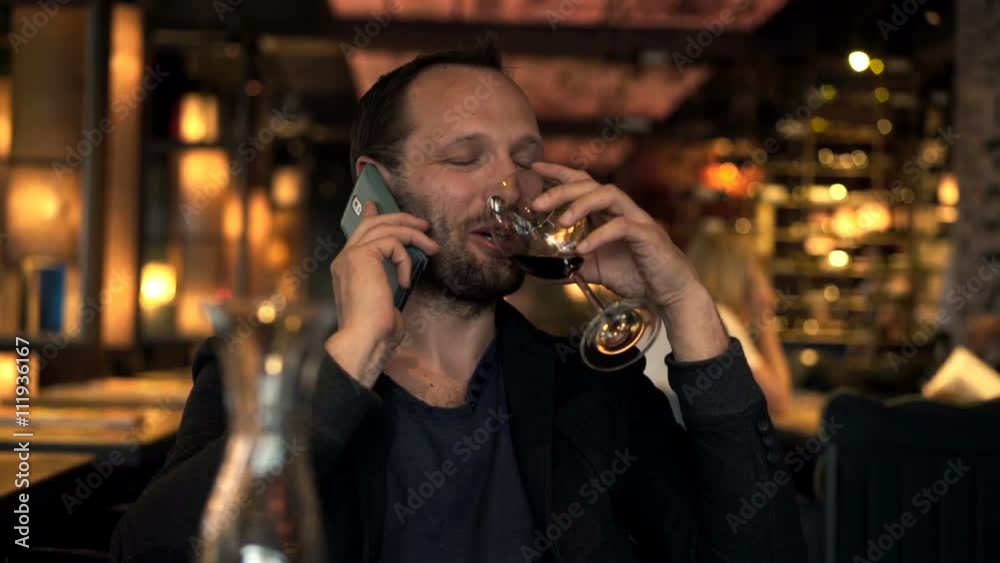 Young man talking on cellphone and drinking red wine in cafe
Young man talking on cellphone and drinking red wine in cafe