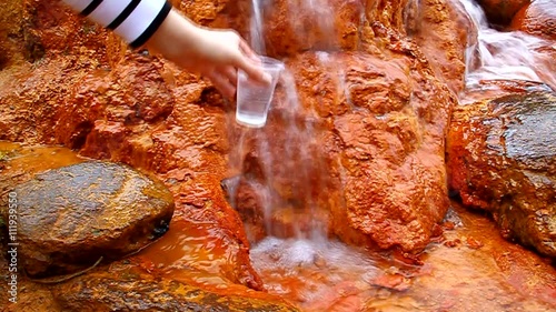 A man pours a glass of Narzan mineral water with iron, which flows over the rocks