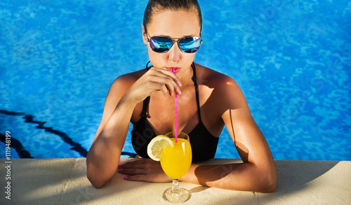 Attractive brunette woman drinking cocktail in the swimming pool