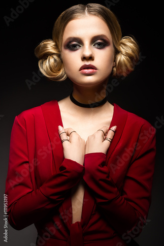 Beautiful girl in a red dress with a deep neckline and black rings on his fingers. The model with bright makeup. Was was made in the studio.
