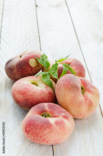 Saturn peaches or UFO, donut, flat peaches on white wood boards  photo