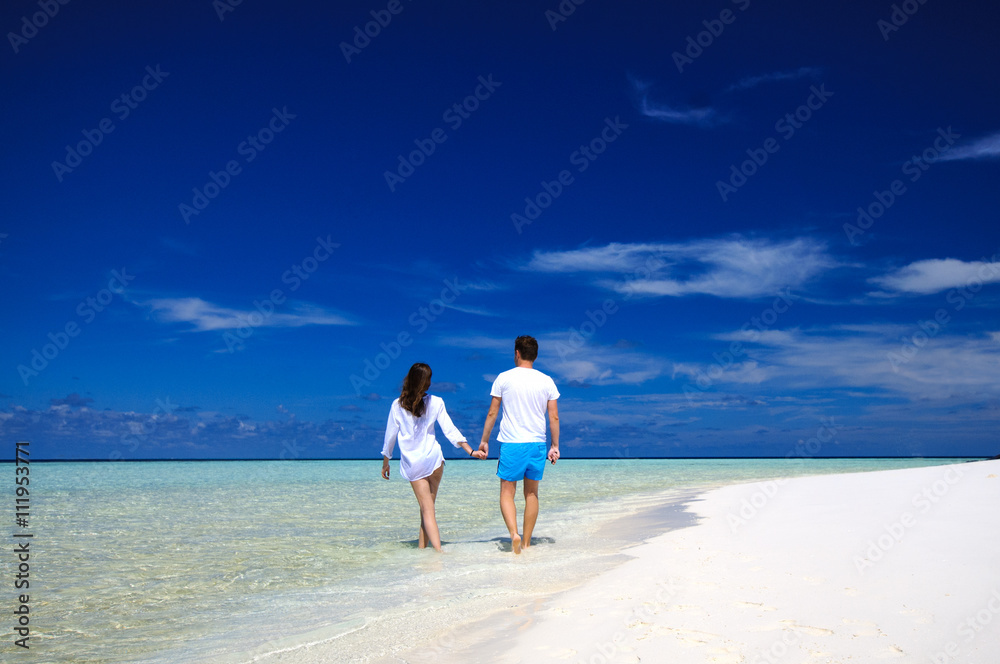 Back view of young couple on white beach. Vacation concept