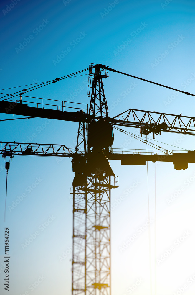 Industrial construction cranes silhouettes on the sunset.