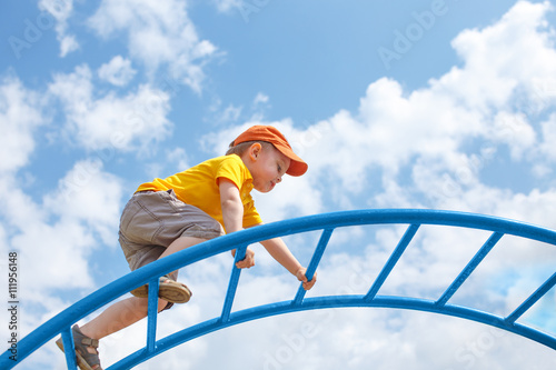 Vászonkép little boy climbs up the ladder on the playground