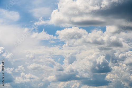 Fototapeta Naklejka Na Ścianę i Meble -  White Cumulus Clouds And Grey Storm Clouds Gathering On Blue Sky
