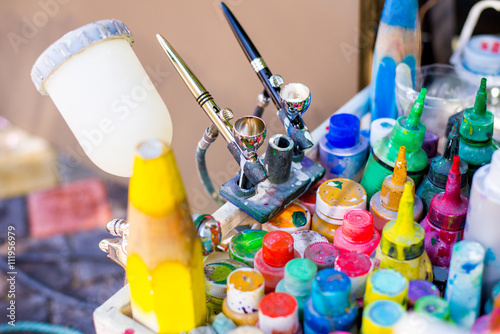 Professional airbrush on a stand with colorful paints in backgroung photo
