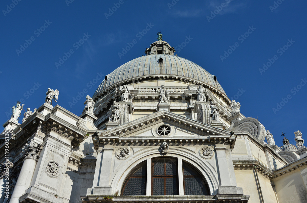 Santa Maria della Salute external decoration. Beautiful domes, belfry and statue from the baroque Saint Mary of Health basilica in Venice, designed by architect Longhena in 1631