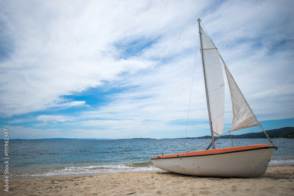 Sail boat on tropical beach with blue water background