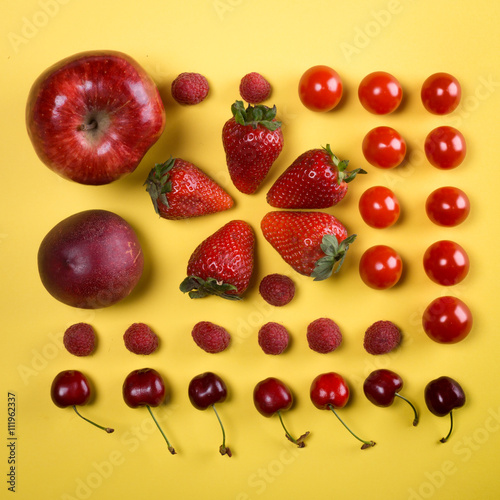 Fototapeta Naklejka Na Ścianę i Meble -  composition en carré de fruits rouges sur un fond jaune