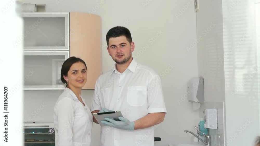 Dentist discussing with pretty female assistant diagnosis of his patient Dentist discussing with pretty female assistant diagnosis of his patient