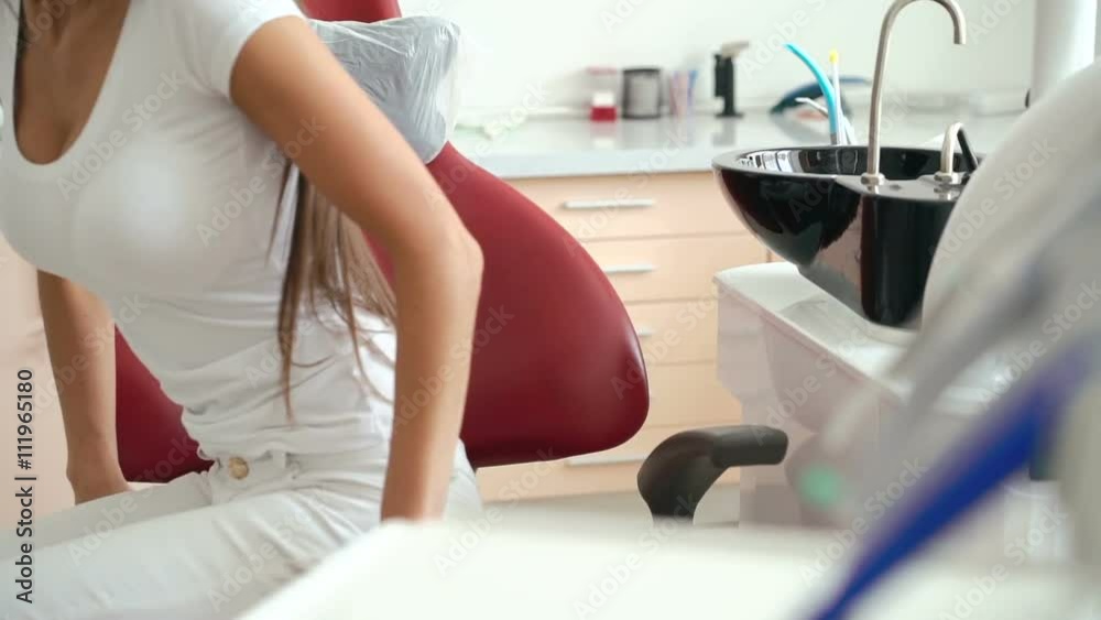 Cute girl sits down in dentist chair and smiling on the camera. Slowly