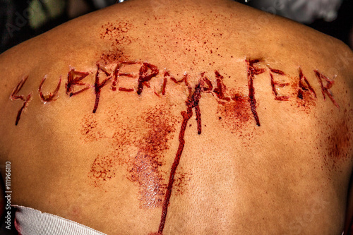 Close up scarred back with the bloody writing subdermal fear. photo