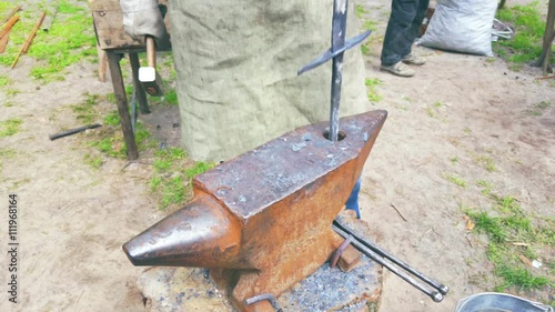 Blacksmith forges a sword on the rusty anvil photo