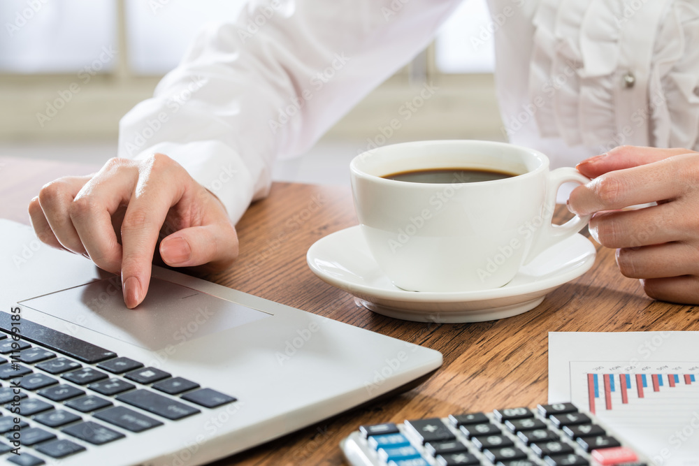 Businesswoman using laptop and drink coffee at desk