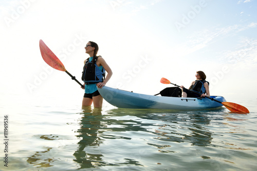 Two young women and blue kayak in Atlantic Ocean