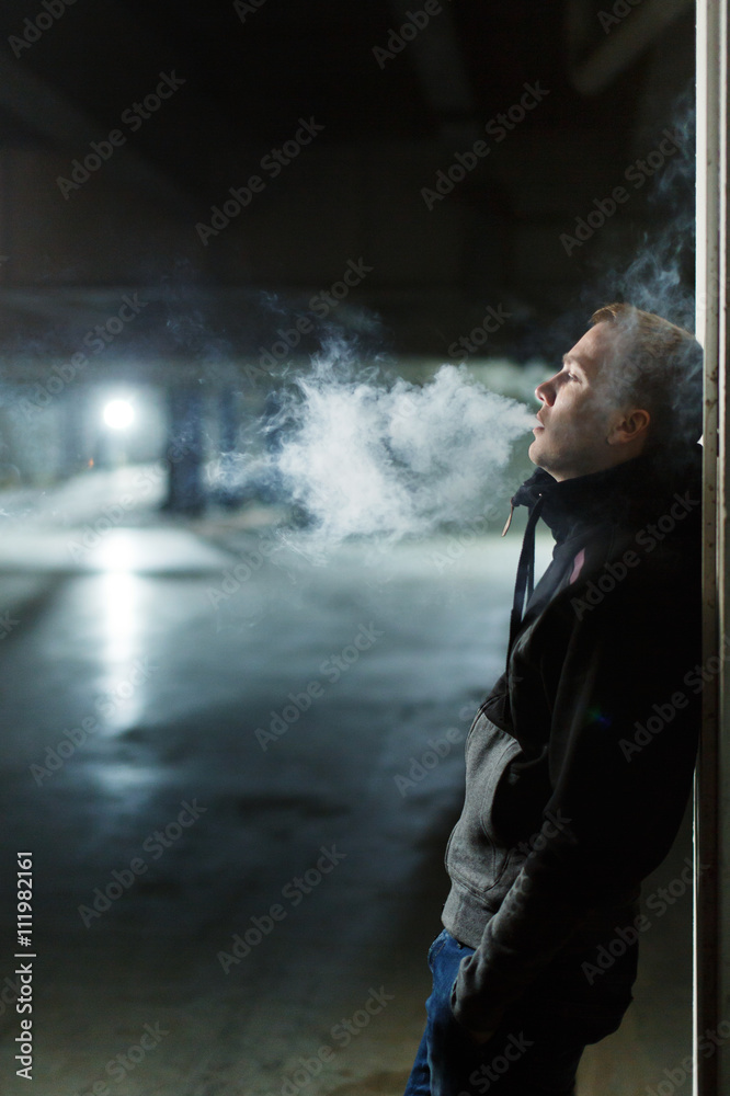 Man smokes a cigarette or hovering or vape e-cigarette.