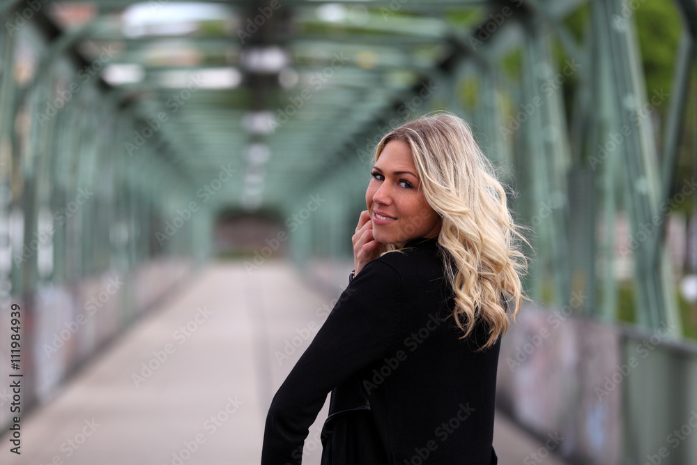 Beautiful blonde woman in black waistcoat looking back over her shoulder